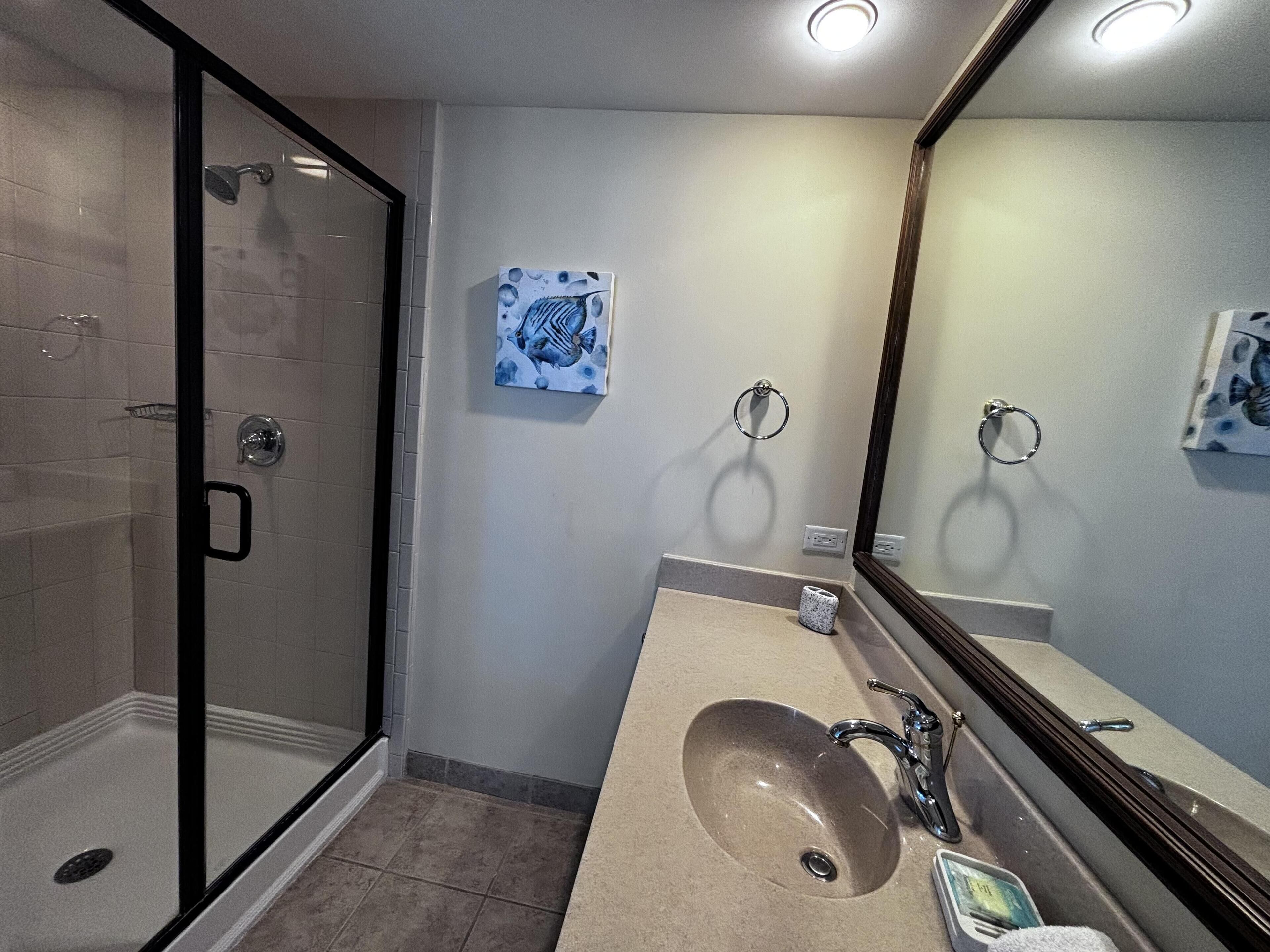 A modern bathroom with a glass shower enclosure, a sink with a mirror, and a towel rack.