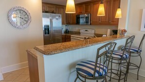 A kitchen with a central island, stainless steel appliances, wooden cabinets, and pendant lighting.