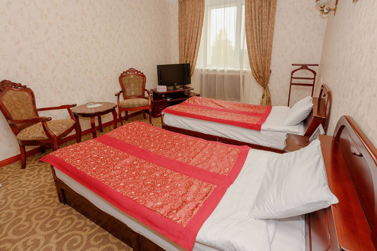 A hotel room with two beds, a television, a chair, and a small table.