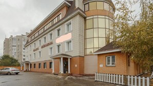 Een meerlaags gebouw met een opvallende ingang, een overdekt gebied en een parkeerplaats.