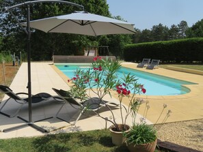 Piscina com espreguiçadeiras e guarda-sol de patamar.