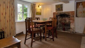 Une salle à manger avec une cheminée en briques, des meubles en bois et une fenêtre avec des rideaux.