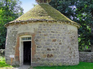 Un edificio in pietra con un piccolo ingresso e un tetto in tegole.