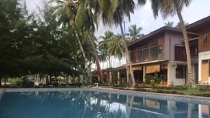 Piscina con reflejo de palmeras y un edificio con balcones.