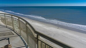 A beach view from a balcony with a railing, a clear sky, and the ocean. - MVG 1510 Oceanfront, Penthouse (North Myrtle Beach)