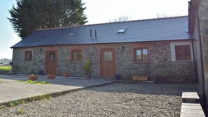A stone building with a sloped roof, multiple windows, and a gravel driveway. - Hen Llaeth - UK11209 (Cwmsychpant, near Lampeter)
