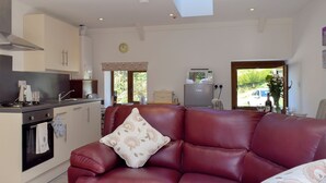 A modern kitchen with a red leather sofa, a clock, and a refrigerator. - Hen Llaeth - UK11209 (Cwmsychpant, near Lampeter)