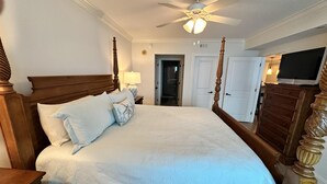 A four-poster bed with a white quilt, a wooden headboard, and a nightstand with a lamp. - MVG 511 3 bedroom 3 bath Oceanfront (North Myrtle Beach)