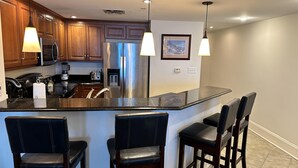 A modern kitchen with a central island, bar stools, stainless steel appliances, and pendant lighting. - MVG 511 3 bedroom 3 bath Oceanfront (North Myrtle Beach)