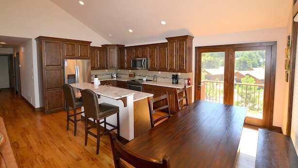 A spacious kitchen with wooden cabinets, a central island with seating, and a large window overlooking a balcony. - The Summit - 3 bedroom 2.5 bathroom home - walk to town (Estes Park)