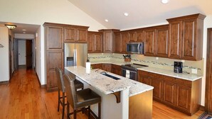 A kitchen with wooden cabinets, a granite countertop, and a stainless steel refrigerator. - The Summit - 3 bedroom 2.5 bathroom home - walk to town (Estes Park)