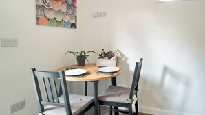 A dining area with a wooden table, two chairs, a potted plant, and a wall-mounted power outlet. - 1 bedroom accommodation in Wainfleet, near Skegness (Wainfleet, near Skegness)