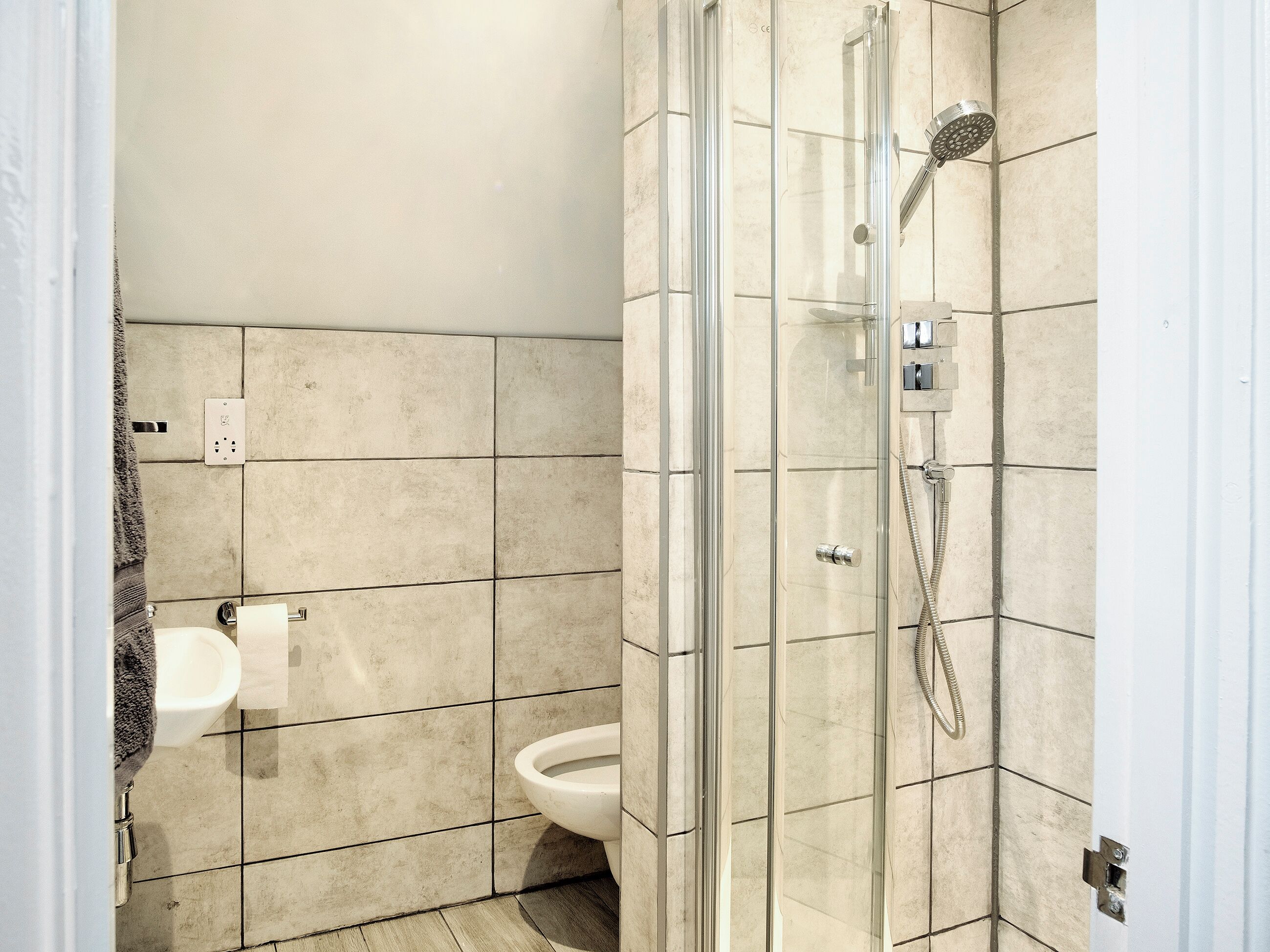 A bathroom with a glass-enclosed shower, a toilet, and a sink.