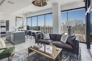 Ein modernes Wohnzimmer mit einer Ledersofa, einem Couchtisch und Blick auf die Stadt durch große Fenster.