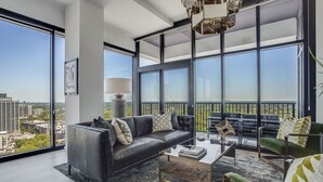 A modern living room with a large window, a sofa, a coffee table, and a chair. - La Brise by Atlanta Luxury Rentals (Atlanta)