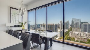 A modern office space with a large table and chairs, a potted plant, and a city view through large windows. - La Brise by Atlanta Luxury Rentals (Atlanta)