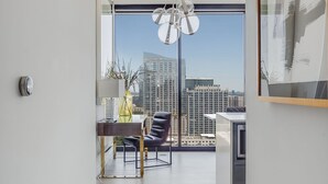 A modern living room with a large window, a dining area, and a view of the city skyline. - La Brise by Atlanta Luxury Rentals (Atlanta)
