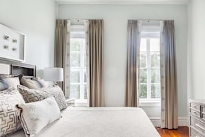 A bedroom with a bed, a bedside table, a lamp, and curtains.