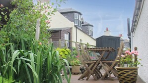 A wooden deck with a chair and a potted plant. - 2 bedroom accommodation in Collieston, near Ellon (Collieston, near Ellon)