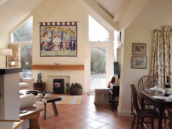 A cozy living room with a fireplace, a dining area, and a large window.