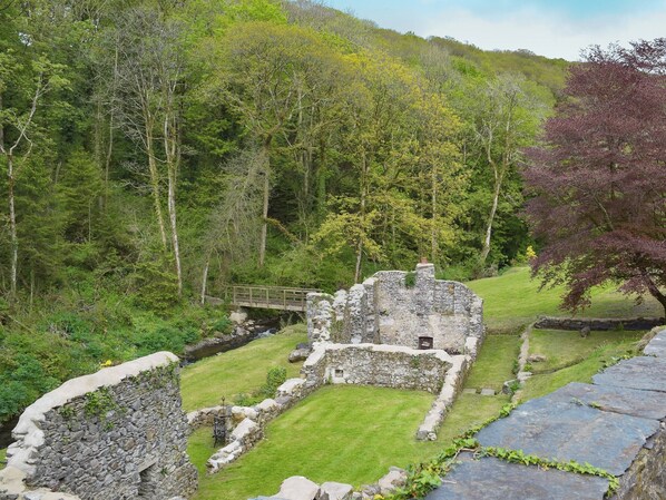 A stone ruin with a grassy lawn and a wooden bridge.