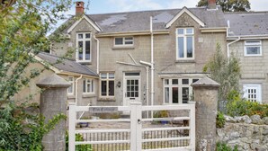 A two-story house with a stone facade, a white gate, and a sign reading "Elm Cottage." - 3 bedroom accommodation in St Lawrence (St Lawrence)