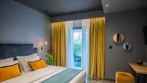 A modern hotel room with a large bed, a desk, and a view of the outdoors. - Olympus Terra Boutique Hotel (Larissa)