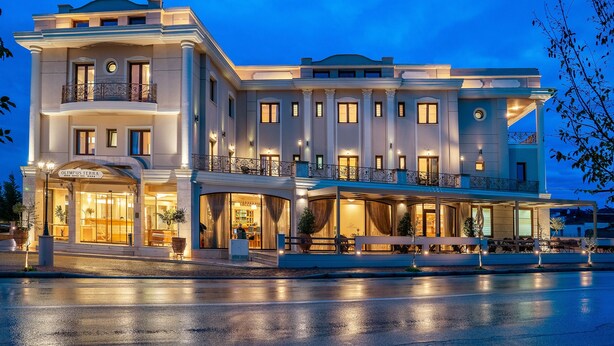 A large, multi-story hotel with a grand entrance, multiple balconies, and a well-lit facade. - Olympus Terra Boutique Hotel (Larissa)