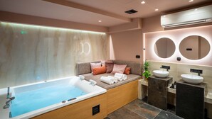 A modern bathroom with a bathtub, two sinks, and a seating area with cushions. - Olympus Terra Boutique Hotel (Larissa)