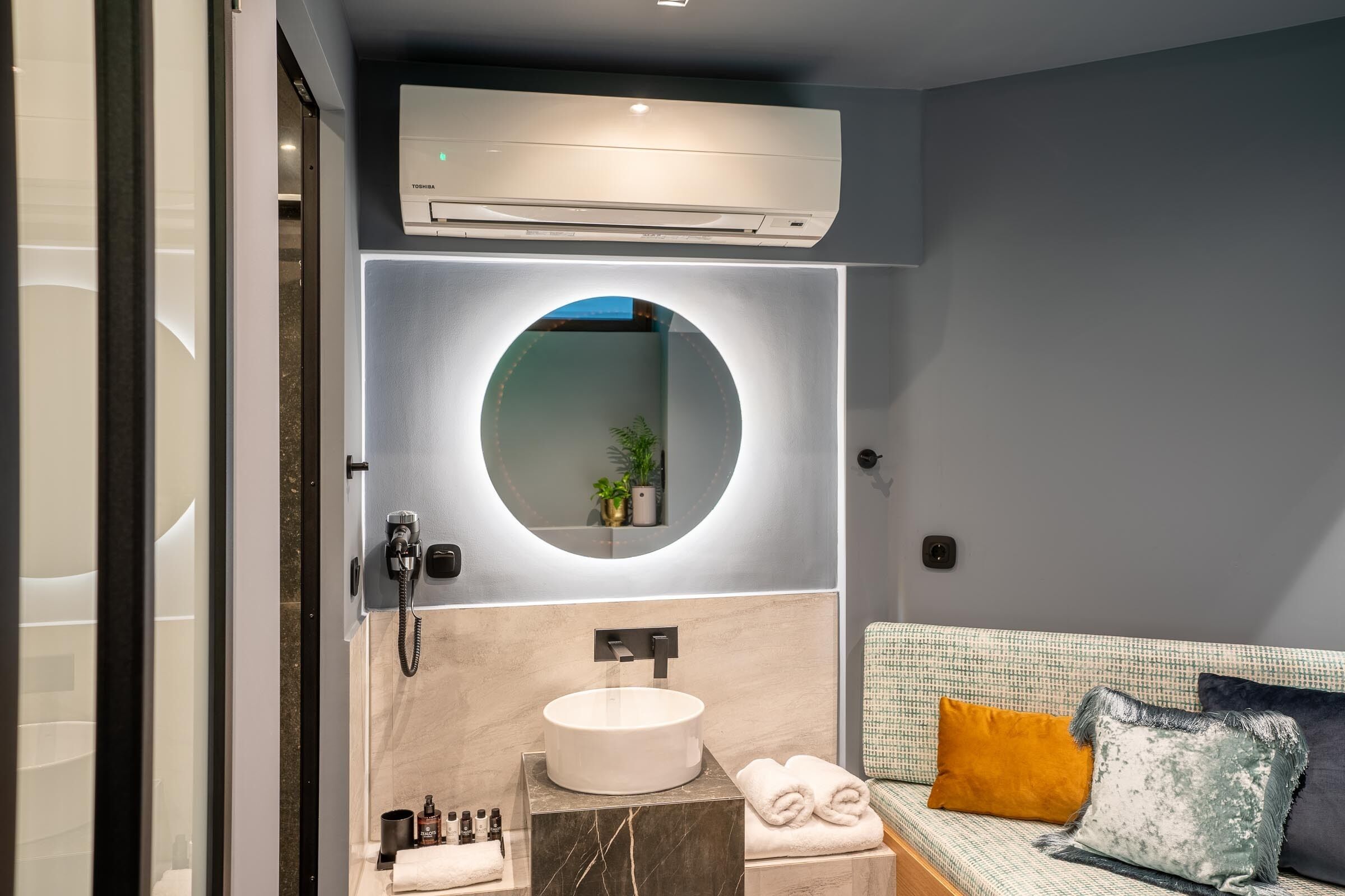 A modern bathroom with a round mirror, a built-in sink, and a towel rack.