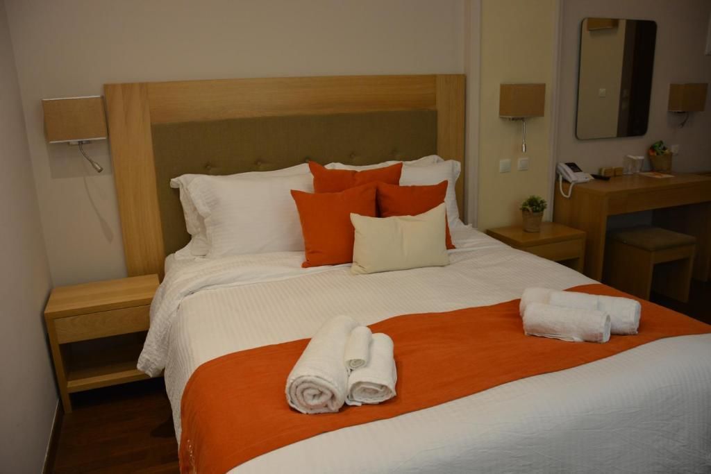 A hotel room with a bed, a wooden headboard, a nightstand, a desk, a mirror, and a telephone.