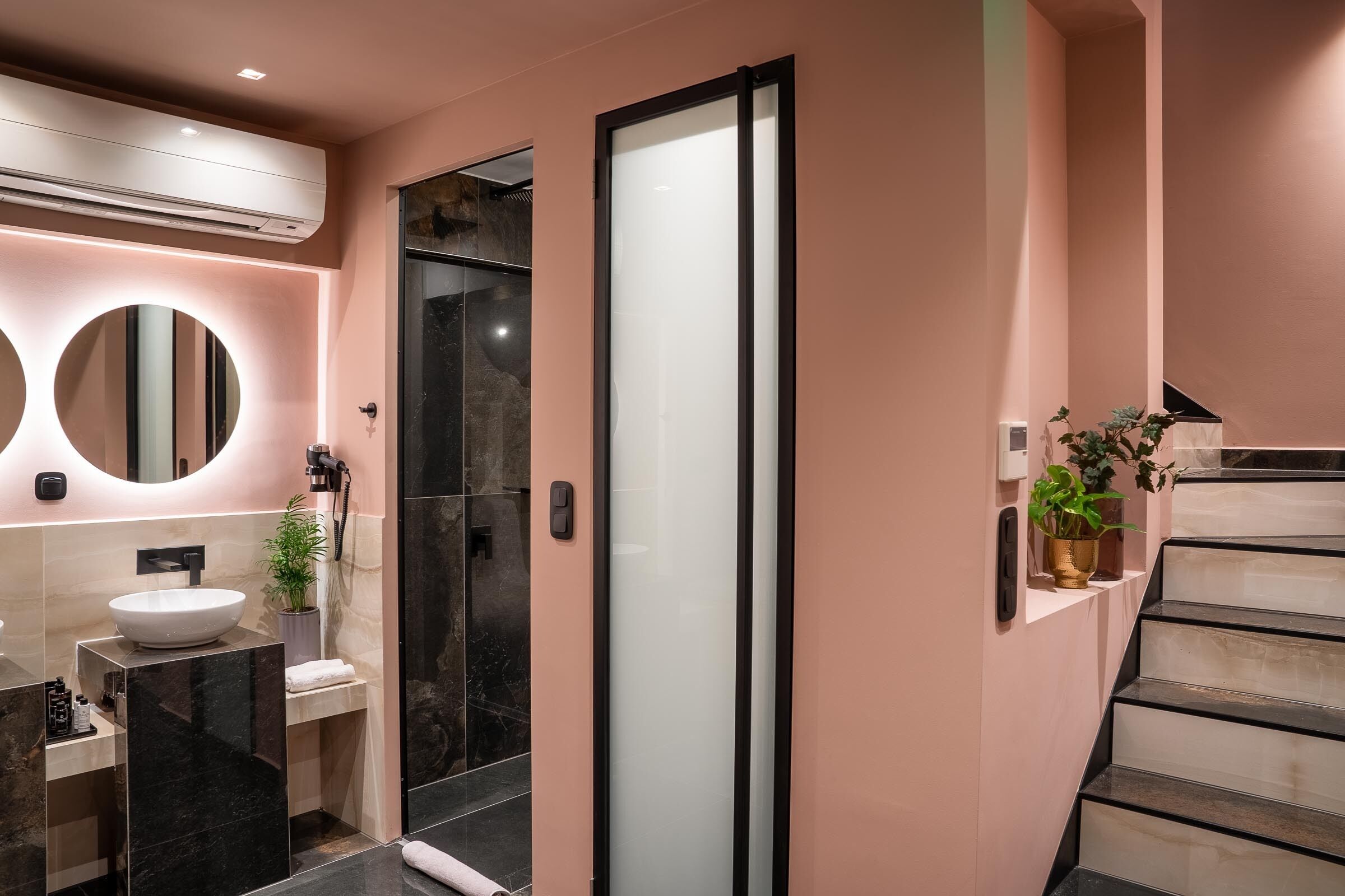 Een moderne badkamer met een grote spiegel, een witte wasbak en een douchecabine van glas.