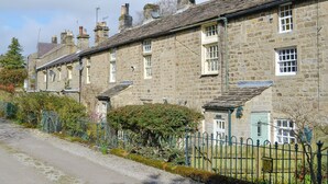 A row of stone houses with traditional architecture, a gravel driveway, and a metal fence. - 2 bedroom accommodation in Bewerley, near Pateley Bridge (Bewerley, near Pateley Bridge)