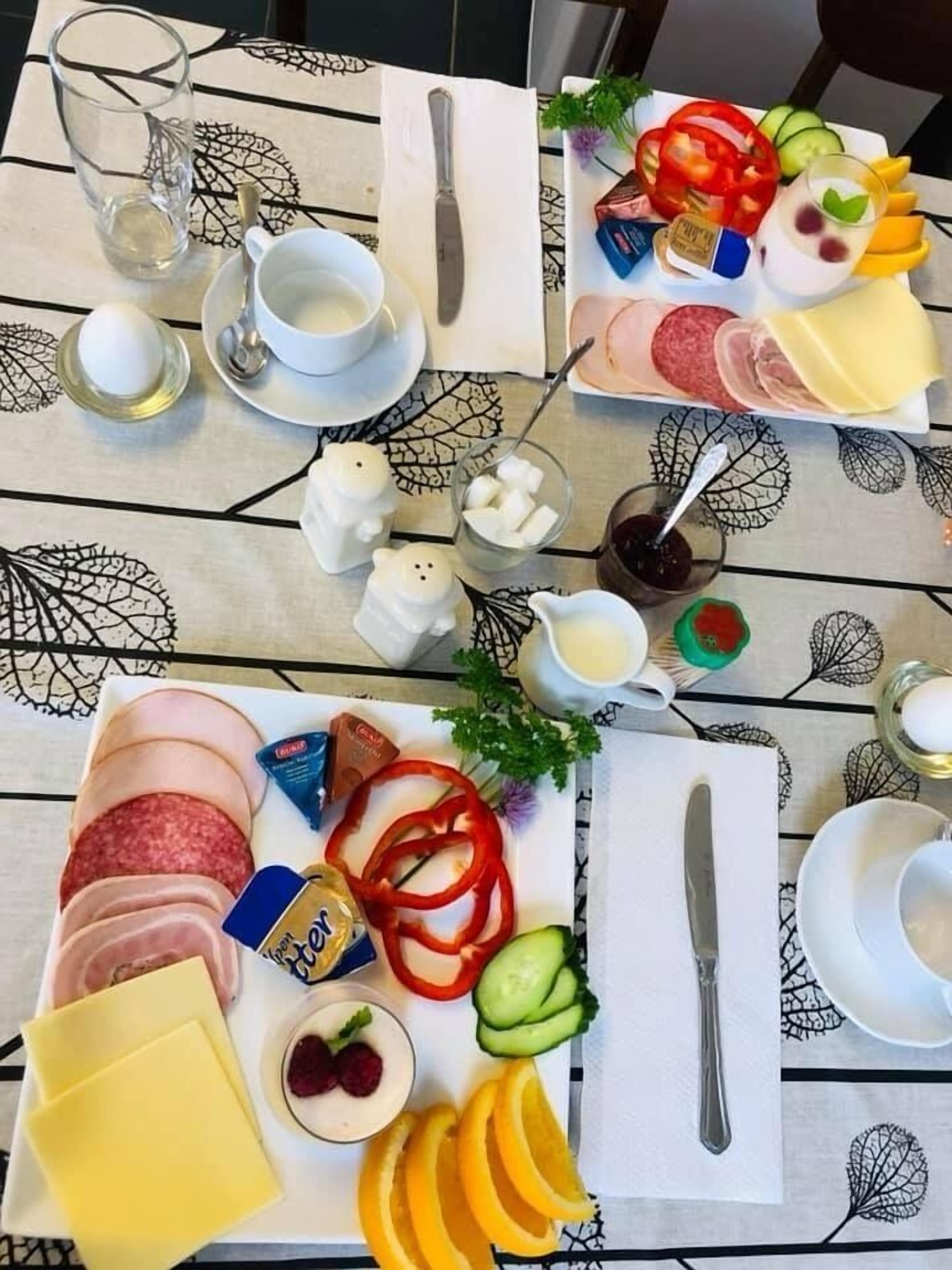 A table set with various food items including cheese, fruits, and condiments, suggesting a meal setup.