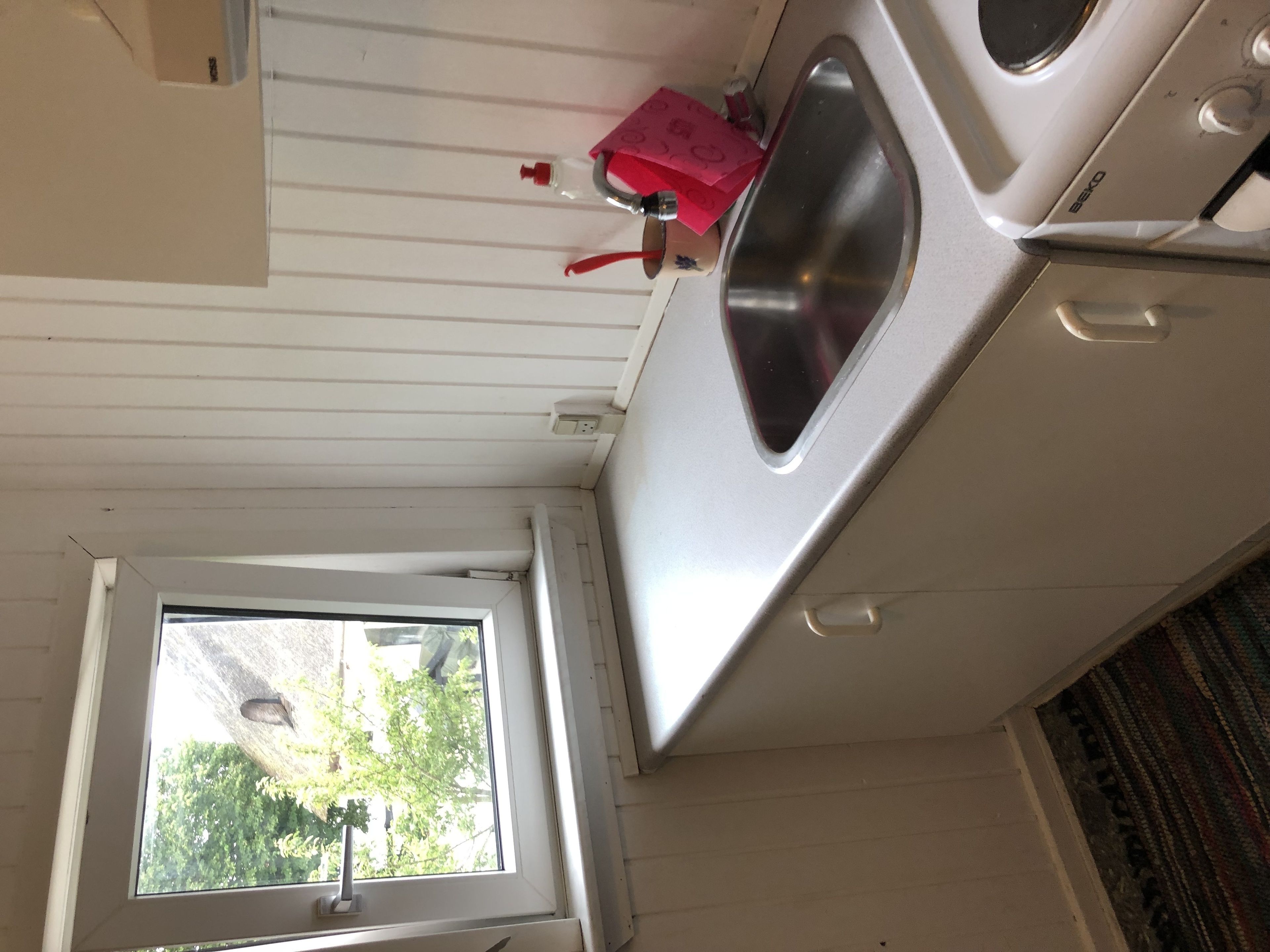Een keuken met een raam, een gootsteen en een fornuis.