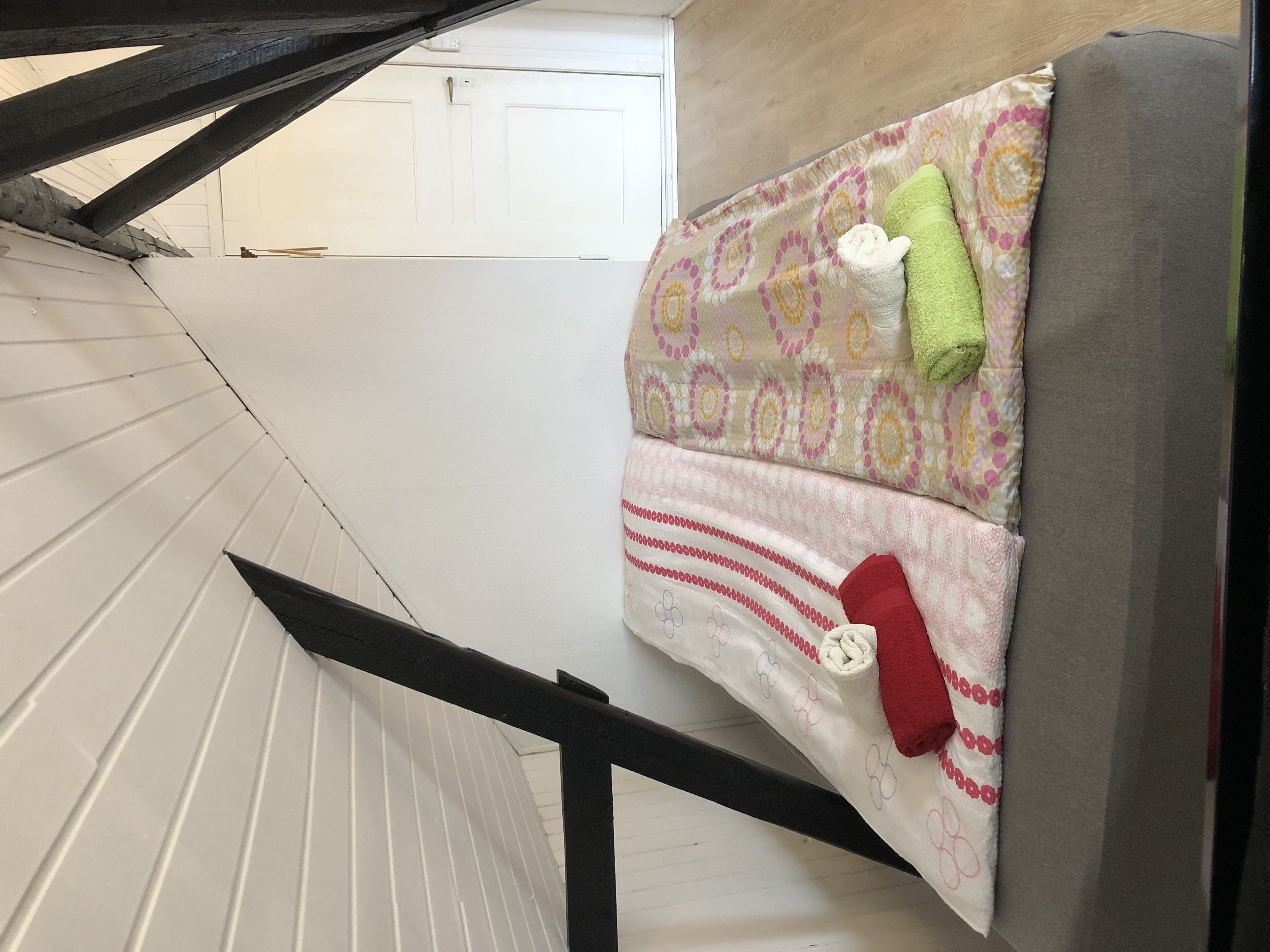A staircase with a white railing and a patterned bedspread with pillows.