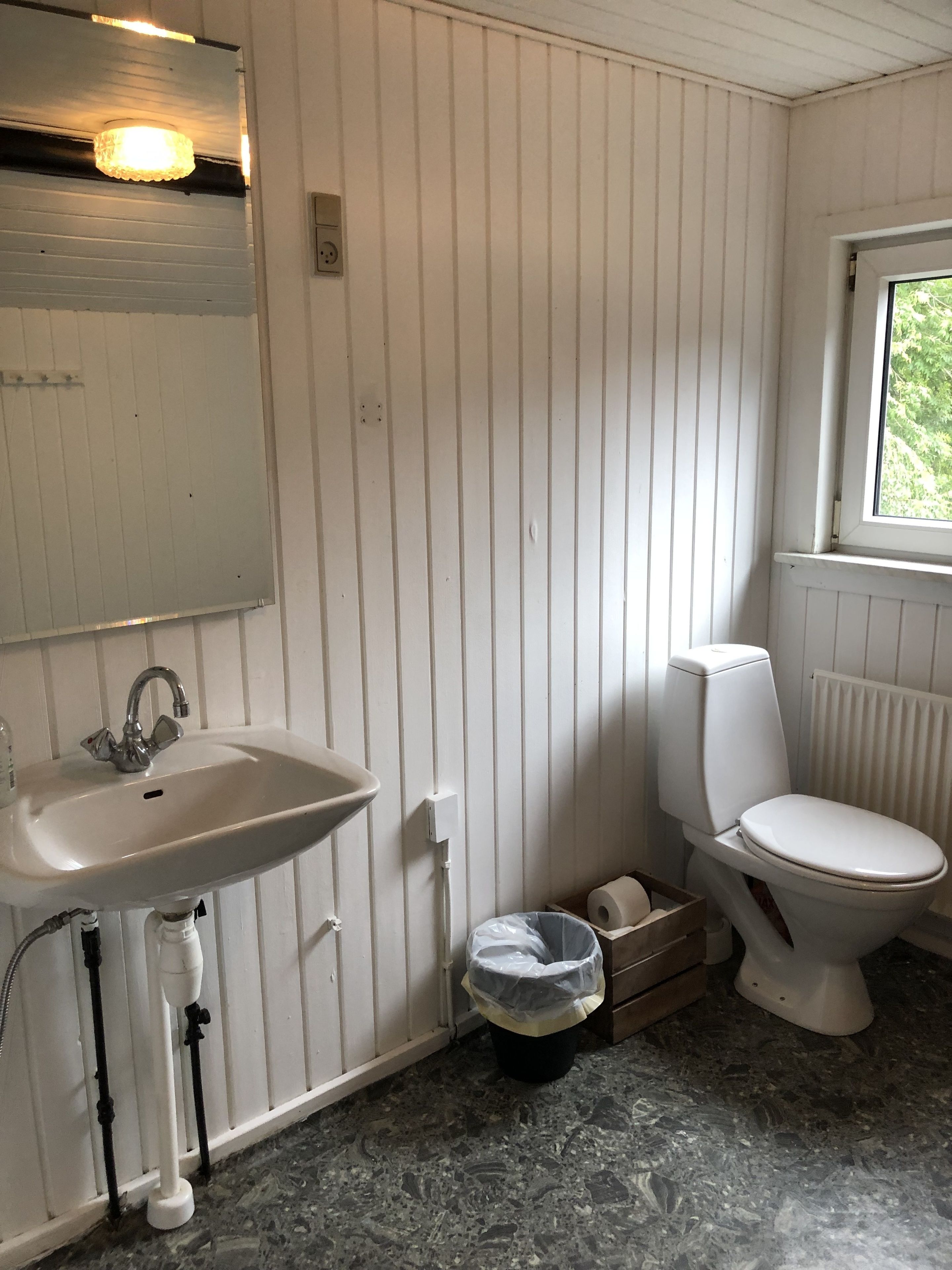 Un baño con lavamanos blanco, inodoro y ventana.
