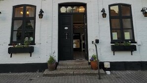 A white building with a black door and windows, labeled "Landevejskroen". - Døstrup Landevejskro & Motel (Skaerbaek)