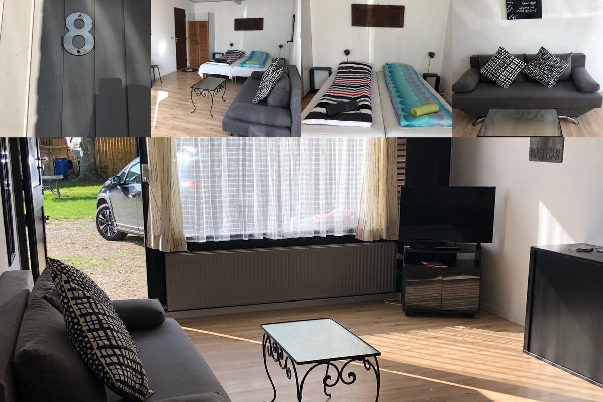 A compact living space with a sofa, two single beds, a TV, and a small table.