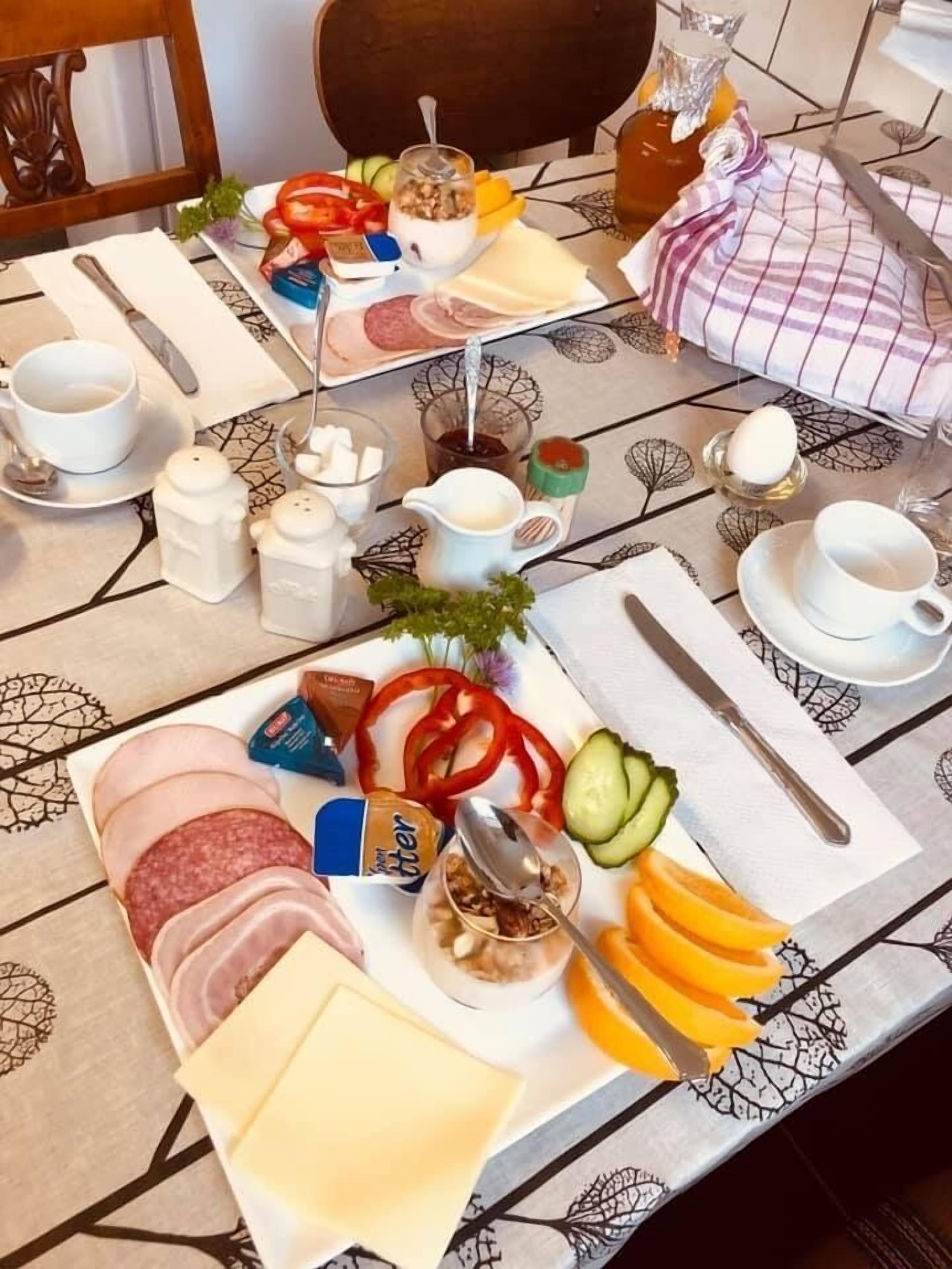 A breakfast table with various food items, utensils, and condiments.