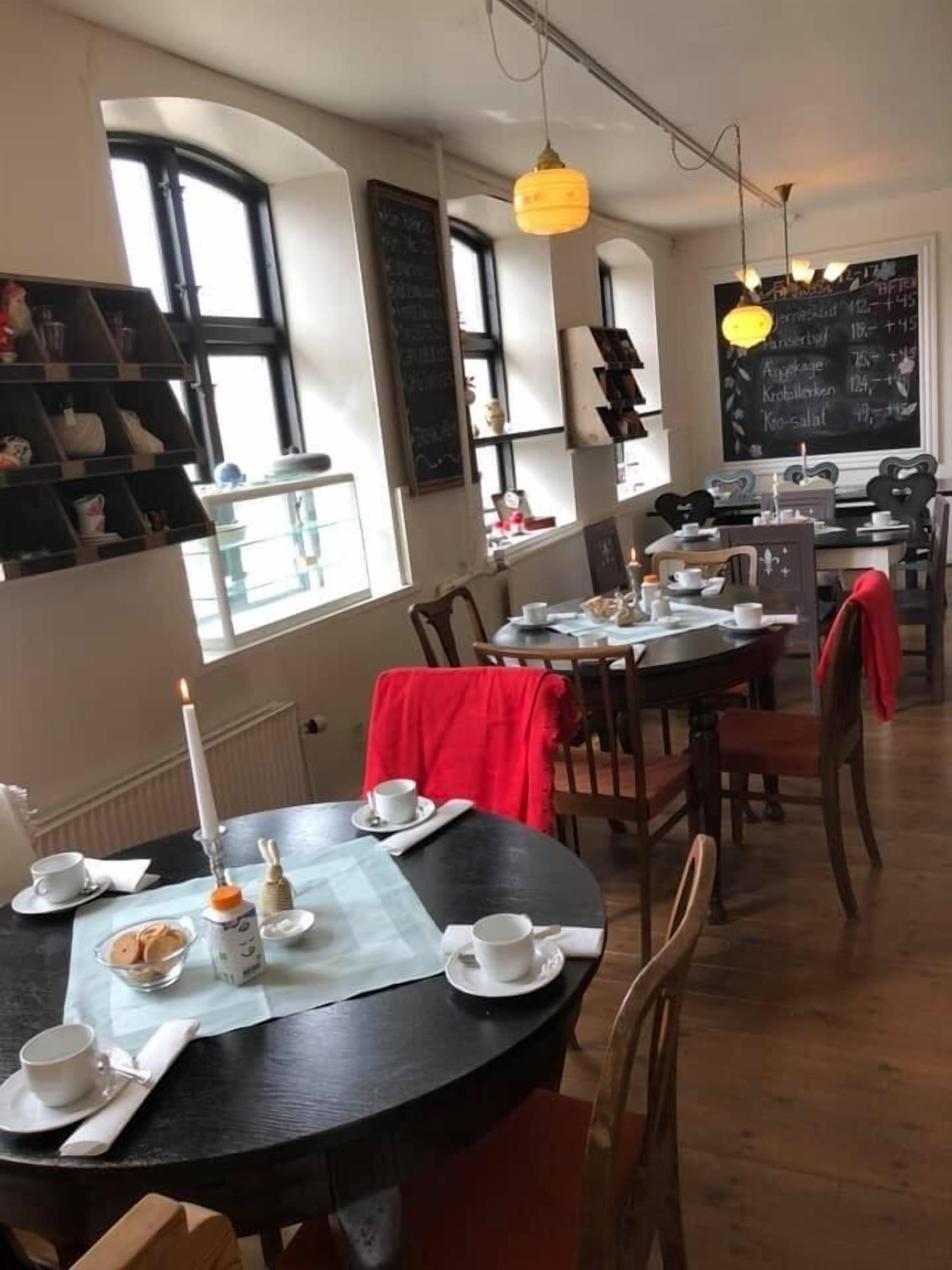 Ein Essbereich mit runden Tischen, Stühlen und einer Tafel mit Speisekarte.