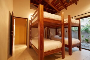 A room with a wooden bunk bed, a door, and a view of a garden. - Hermandad, Short Walk to Surfing Beach | Family Retreat, Gorgeous 4 BDR home located very close to the Beach Dog Cafe  (Nosara)