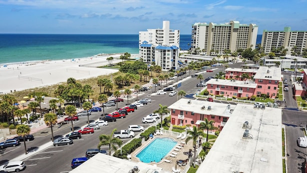 A hotel with a rooftop pool, a beach view, and a parking lot. - 🌴 Gulf Winds Studio — Balcony Views & Sleep Number Comfort by the Beach (St. Pete Beach)