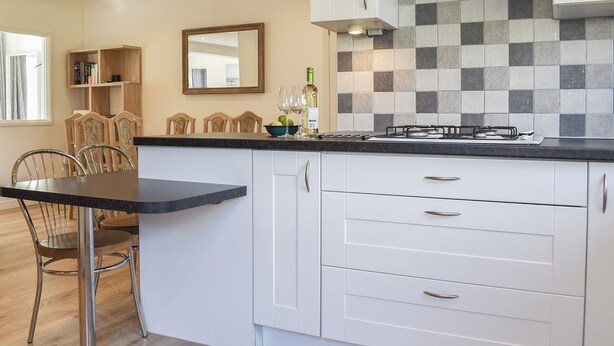 A modern kitchen with white cabinets, a black countertop, and a tiled backsplash. - 2 bedroom accommodation in Carlyon Bay, near St Austell (Carlyon Bay, near St Austell)