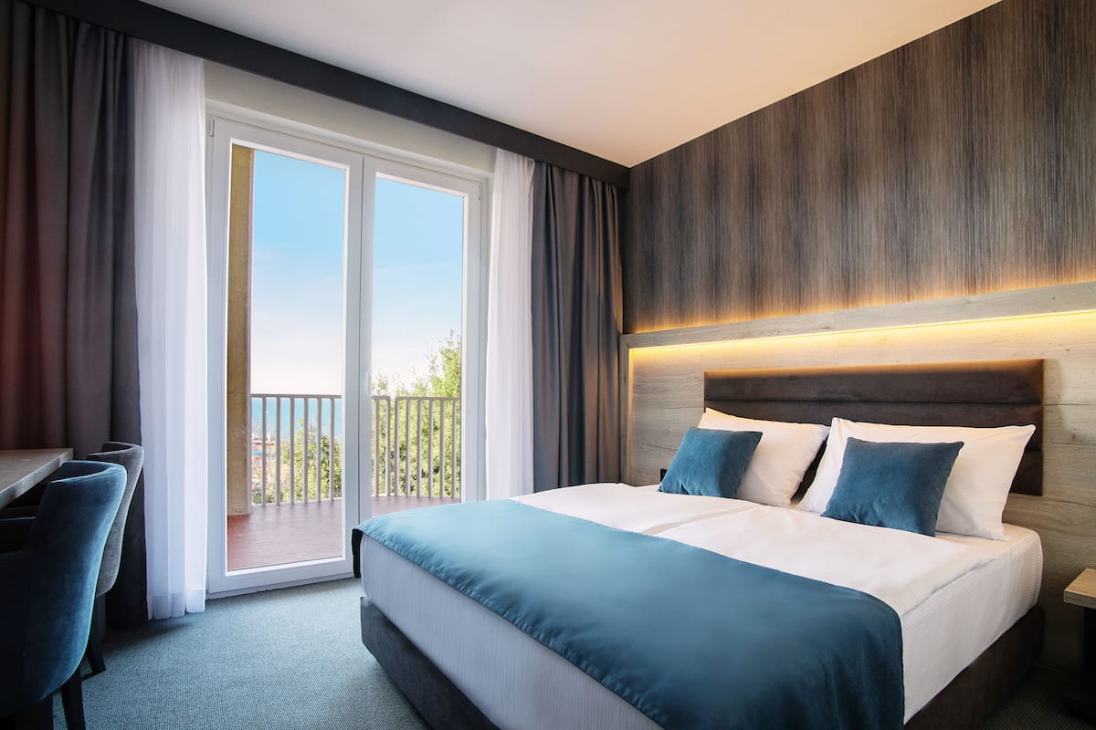 Quarto de hotel com uma cama grande, varanda e escrivaninha.