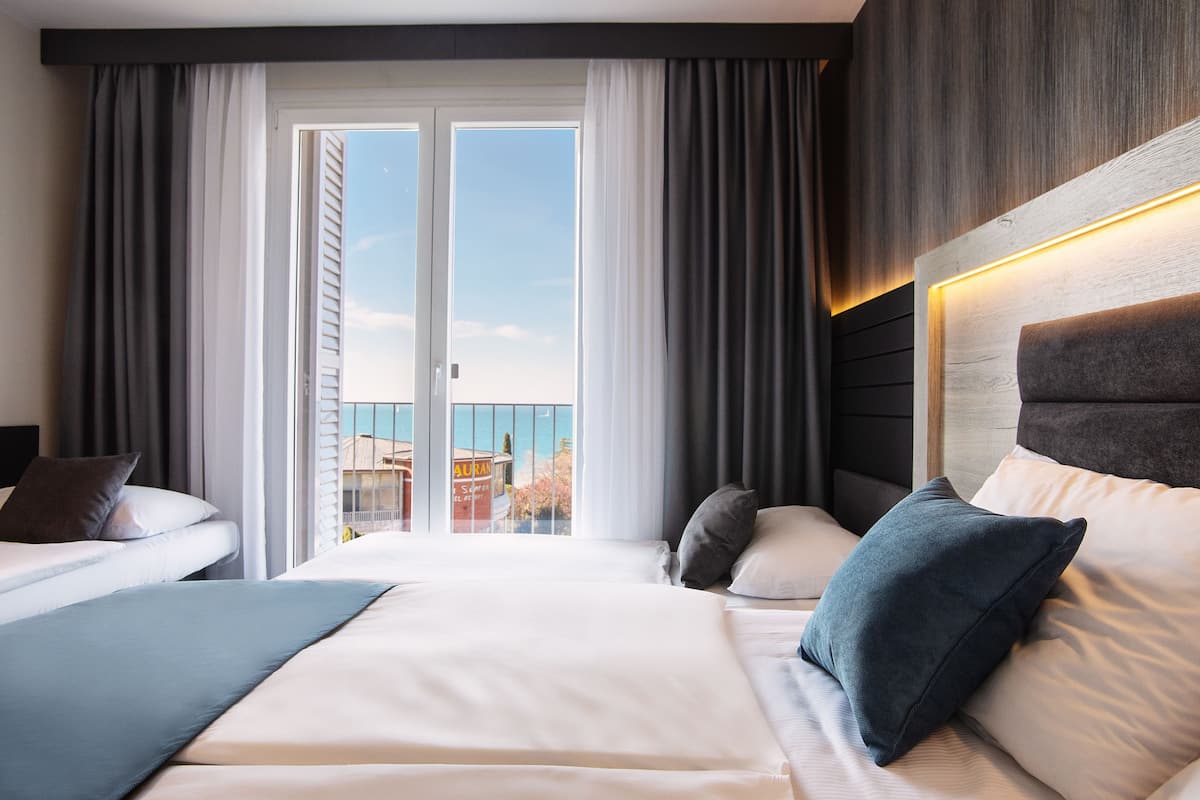 Quarto de hotel com uma cama grande, duas almofadas, cabeceira e vista exterior por uma porta deslizante.