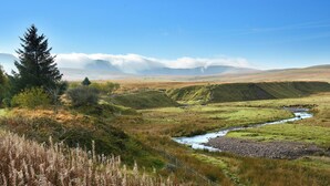 A natural landscape with a river, grassy fields, and a mountain range in the background. - 3 bedroom accommodation in Llangwm, near Usk (Llangwm, near Usk)