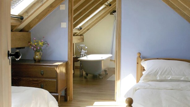 A bedroom with a wooden ceiling, a bed, a dresser, and a window with a view of a bathroom. - 3 bedroom accommodation in Llangwm, near Usk (Llangwm, near Usk)