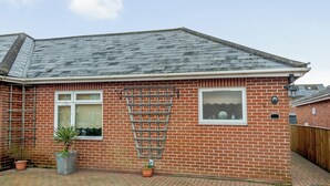 A brick house with a tiled roof, a window, and a small garden area with potted plants. - 1 bedroom accommodation in Cawston, near Aylsham (Cawston, near Aylsham)