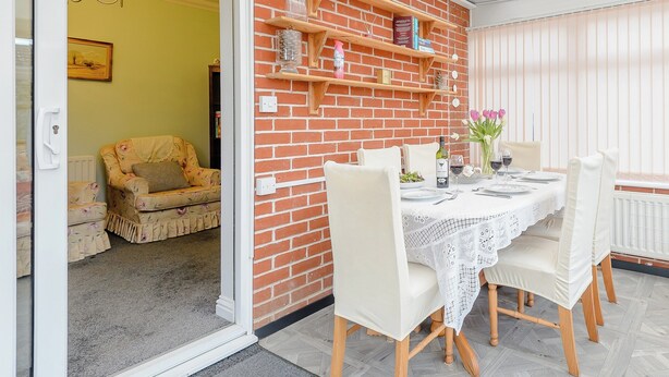 A dining area with a brick wall, wooden shelves, and a table set for two. - 1 bedroom accommodation in Cawston, near Aylsham (Cawston, near Aylsham)